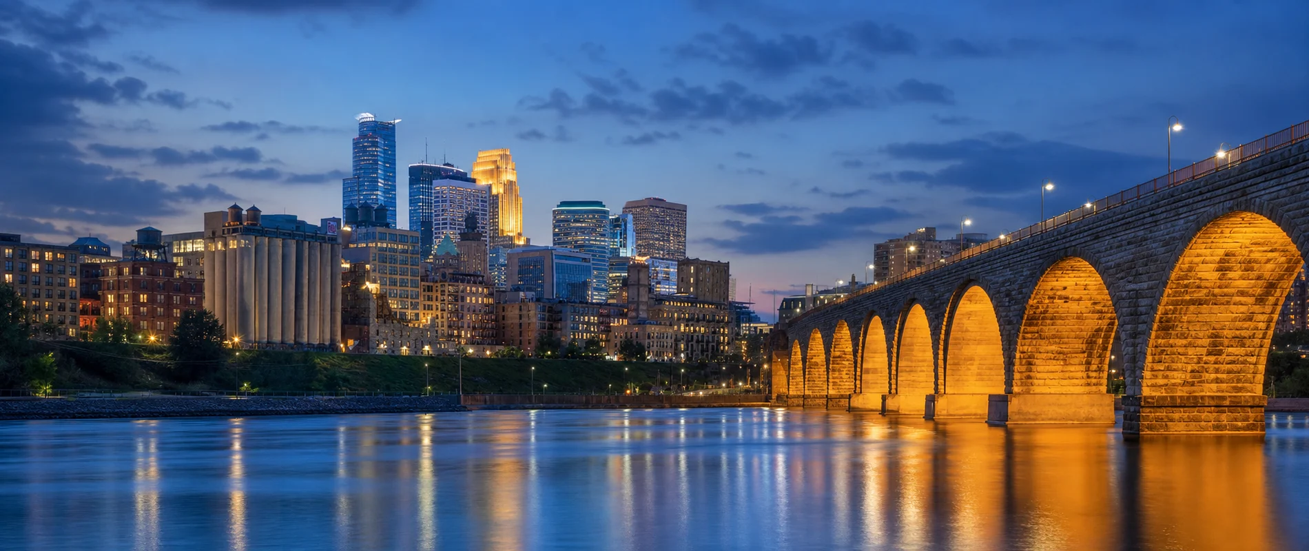 Minneapolis skyline and the lit Stone Arch Bridge over the Mississippi River at blue hour